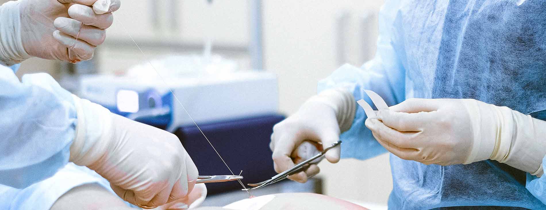 two surgical professionals applying stitches